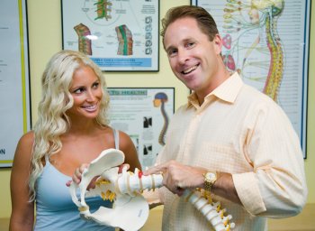 Chiropractor Michael Dorausch demonstrating lumbar disc herniation on spinal model
